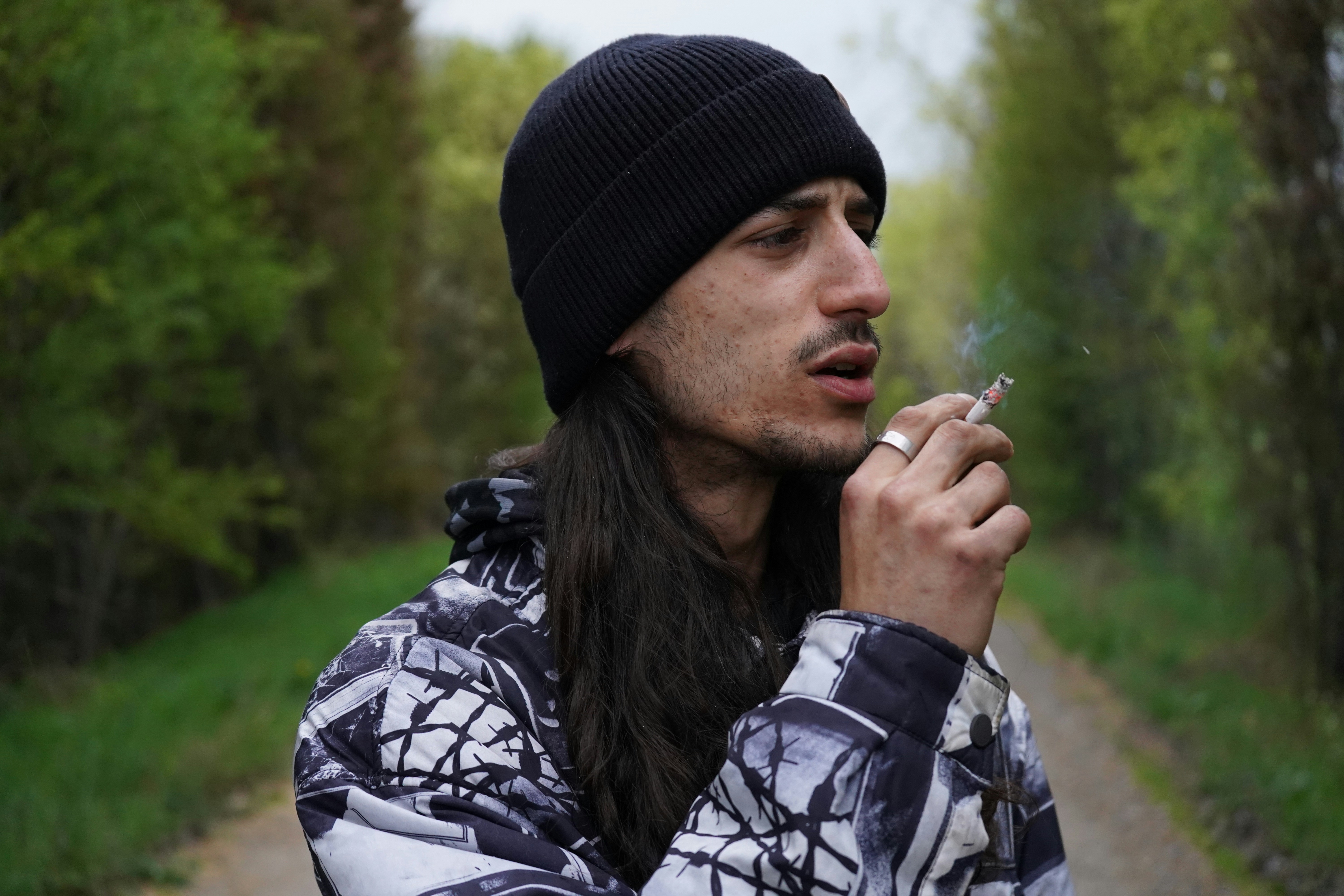 a man with long hair is smoking a cigarette