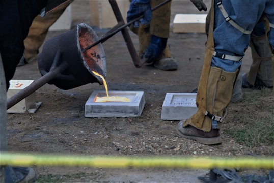 Molten bronze being poured carefully into a ceramic mold.