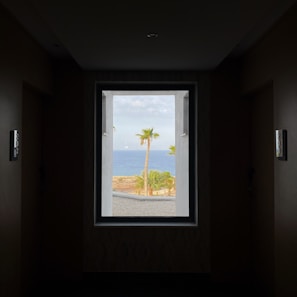 Cozy deluxe room with airy windows opening to palm trees and ocean breeze