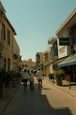 a group of people walking down a street next to tall buildings