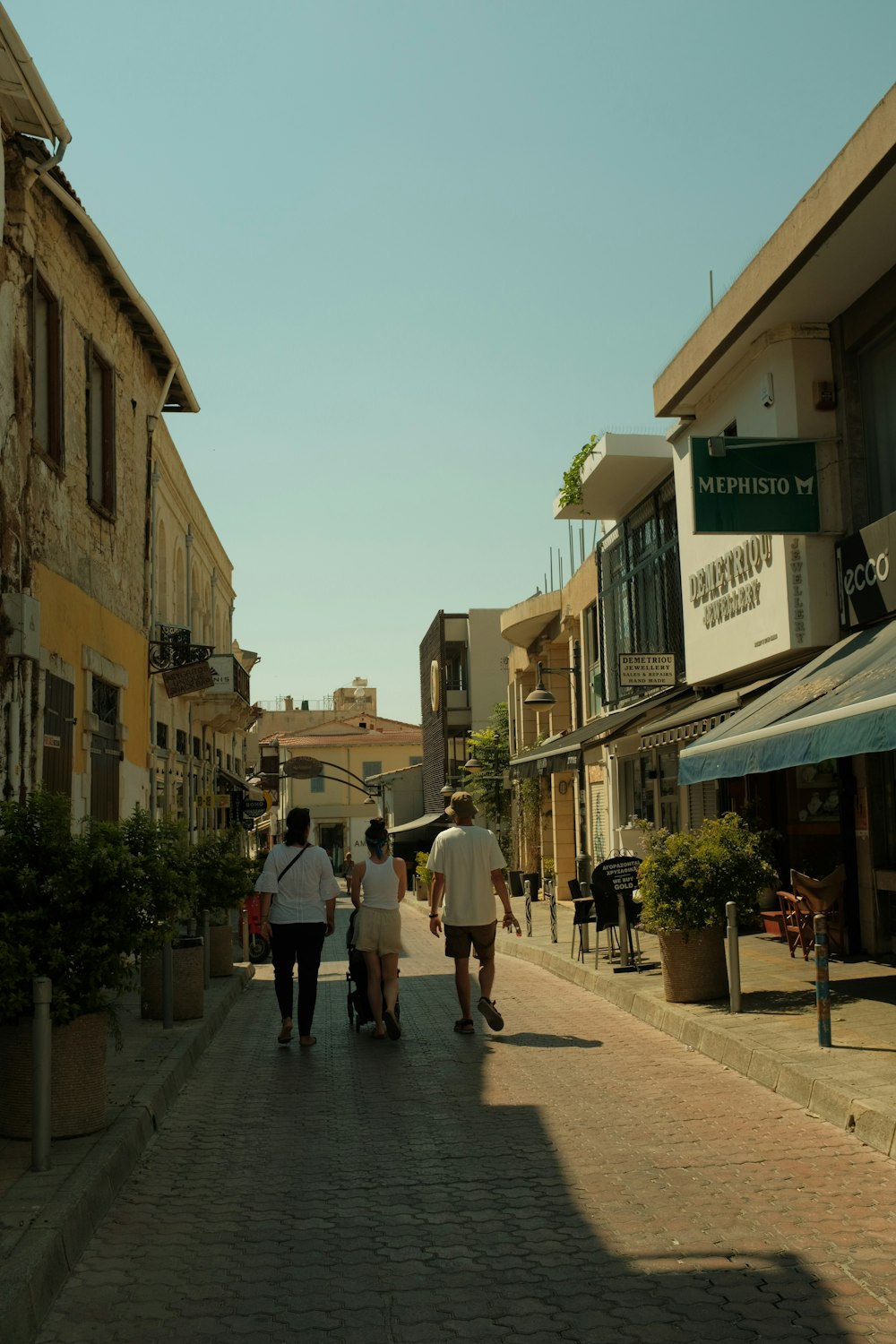 a group of people walking down a street next to tall buildings