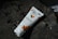 A tube of Bio'l Beauty Argan Oil cream lies on a dark rock surface, surrounded by shadows of leaves. The packaging features orange fruit illustrations, suggesting a natural theme.