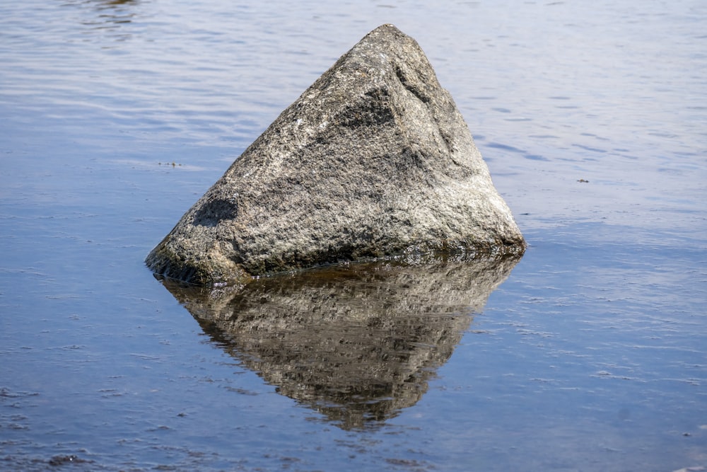 una grande roccia seduta nel mezzo di uno specchio d'acqua