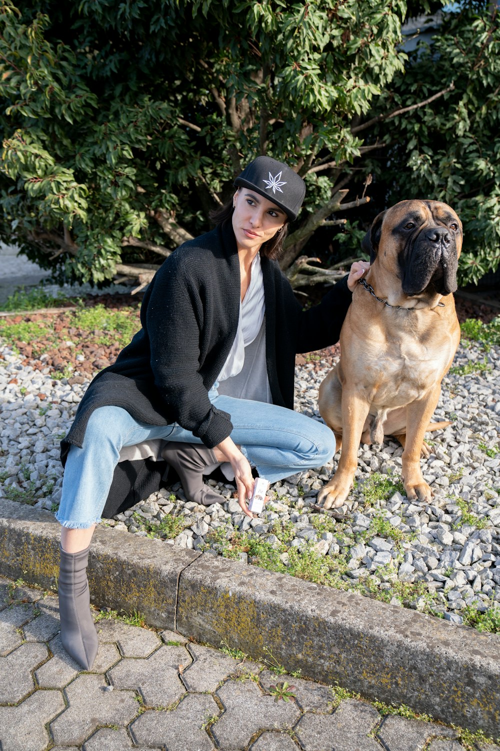 a woman sitting next to a dog on a sidewalk