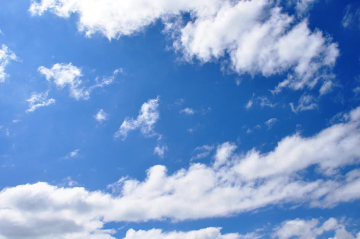 a blue sky with white clouds and a plane in the distance