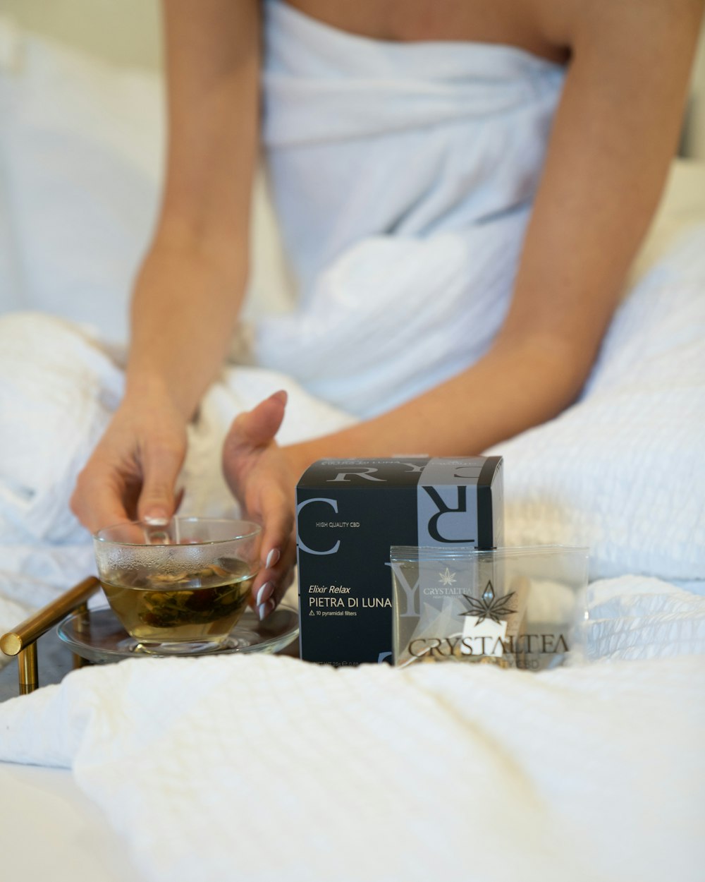 a person sitting on a bed with a glass of tea