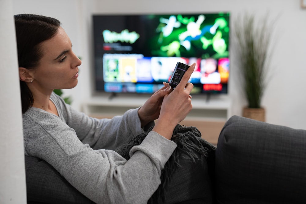 a woman sitting on a couch looking at her cell phone