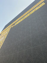 Close-up of a gold-finished CNC-cut Islamic calligraphy frame glowing softly against an ivory parchment background.