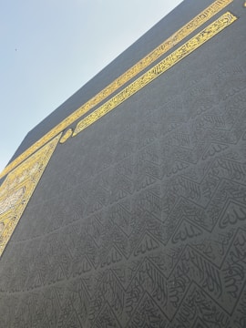 A close-up of intricate Islamic calligraphy in black ink on textured parchment.