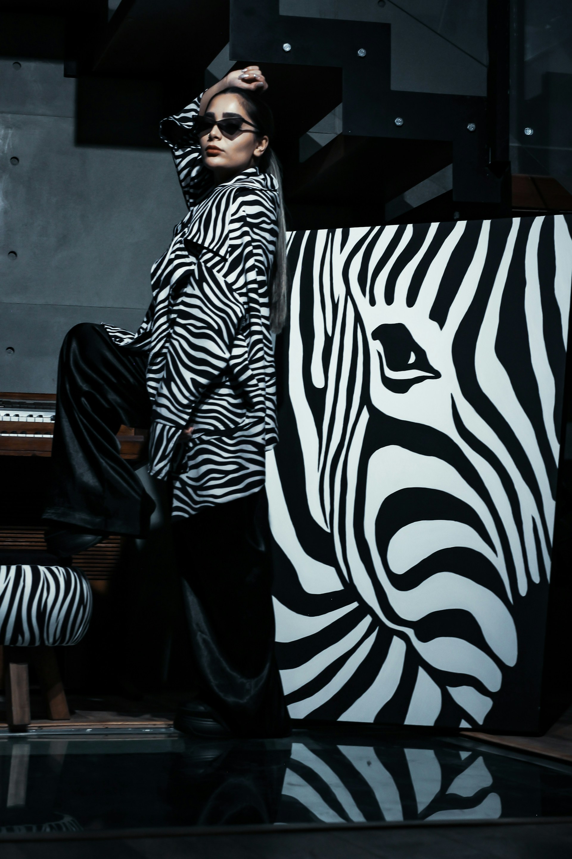 a woman standing next to a zebra in front of a piano