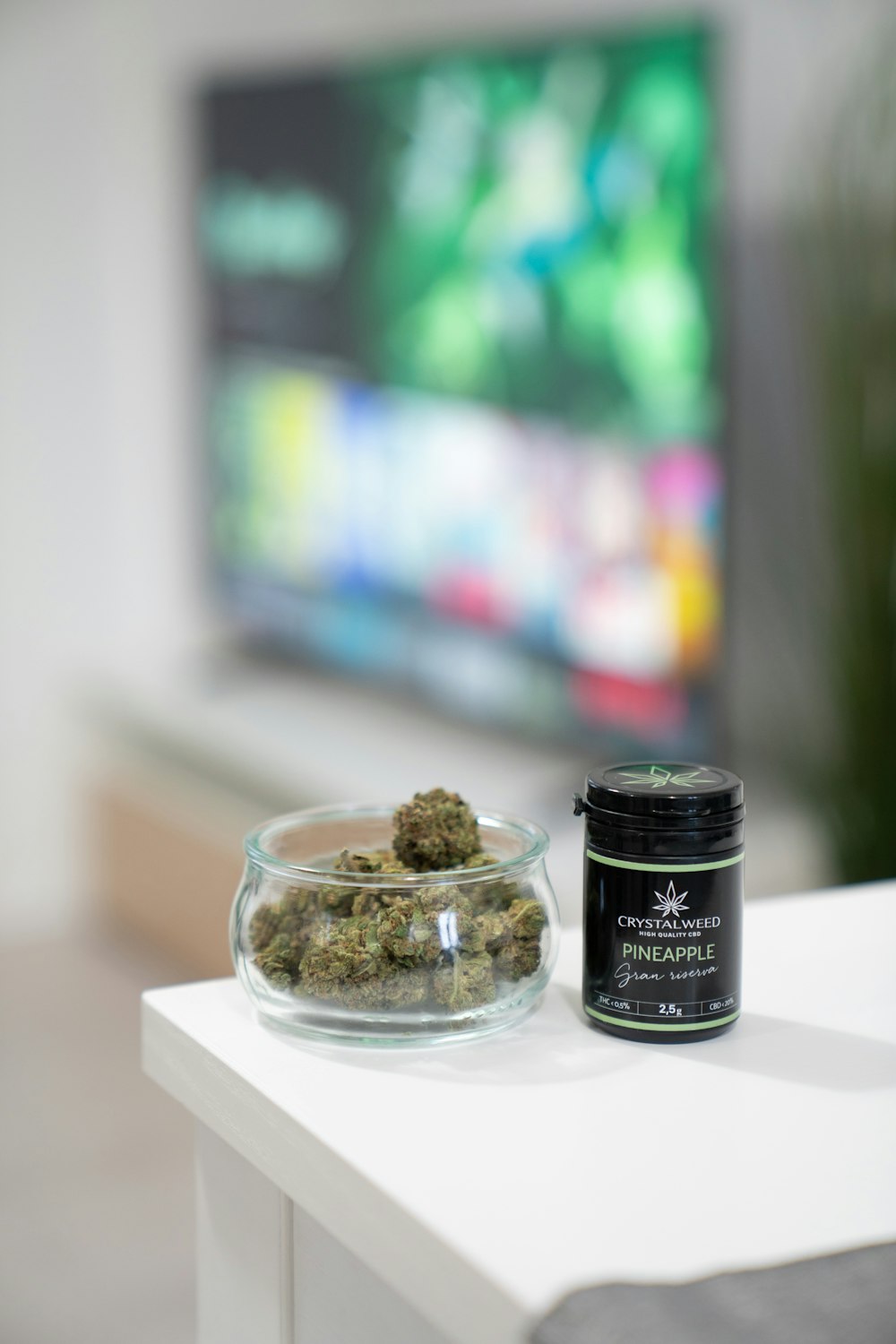 a glass bowl of marijuana next to a tv