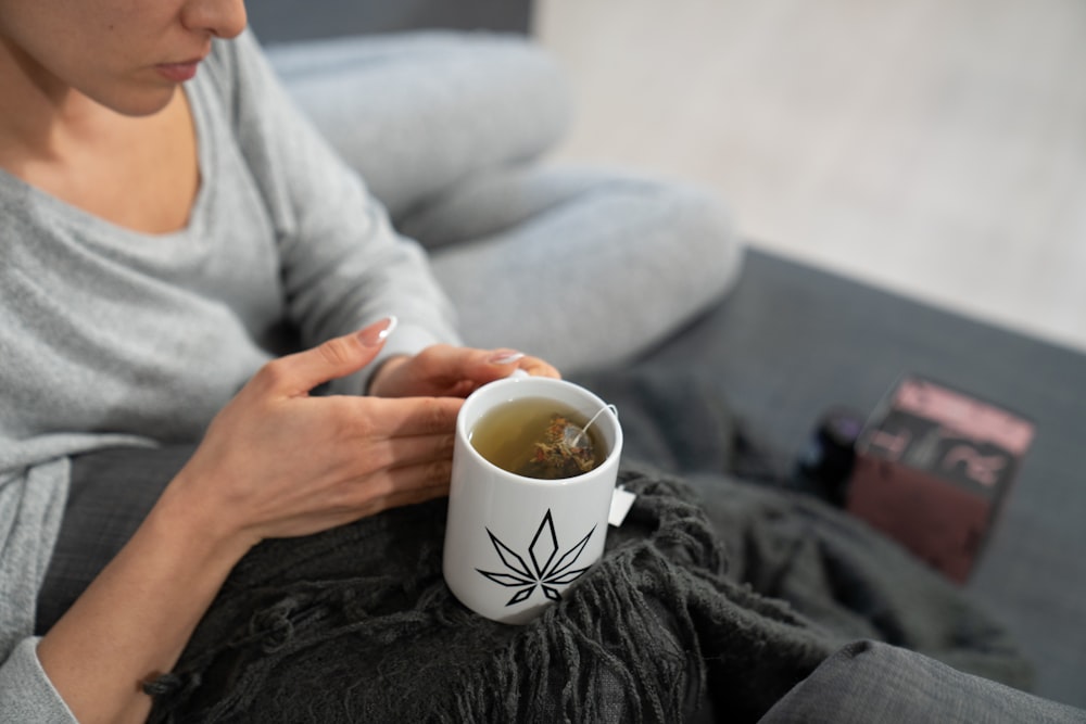 a woman sitting on a couch holding a cup of tea