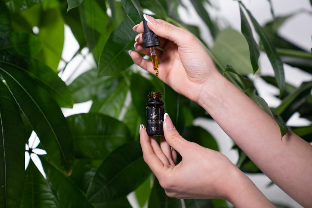 a woman is holding a bottle of essential oil