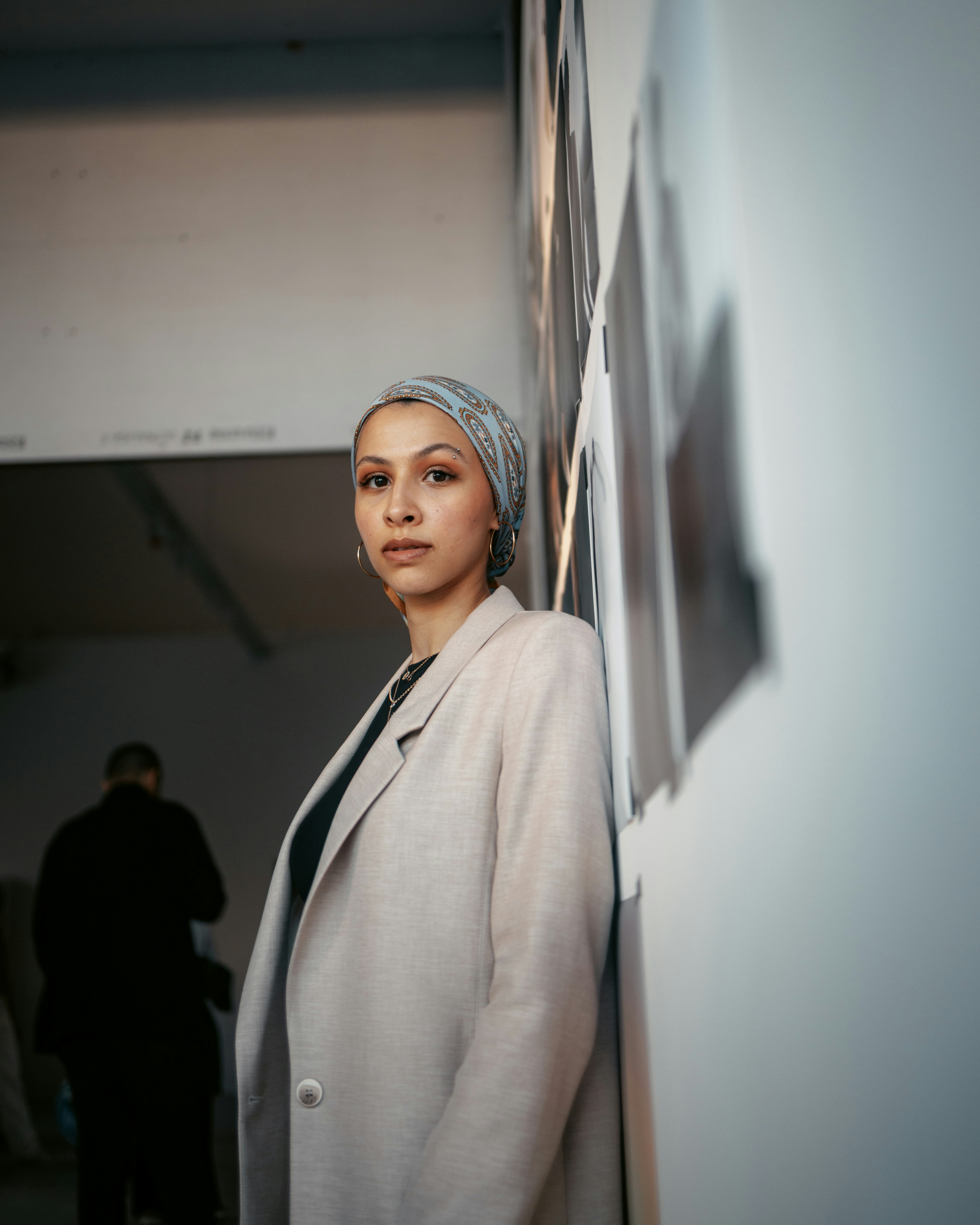 a woman standing next to a wall with pictures on it