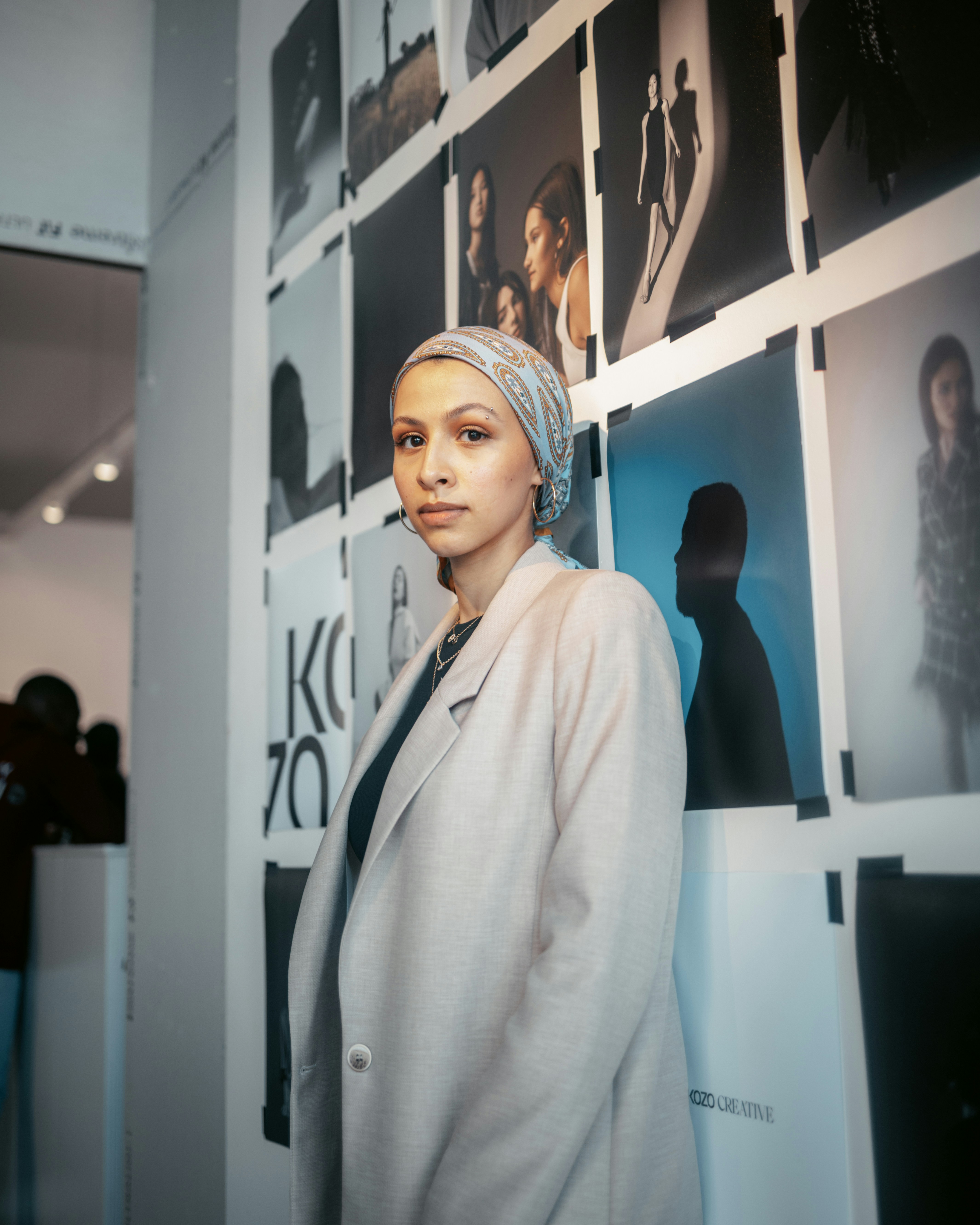 a woman standing in front of a wall with pictures on it