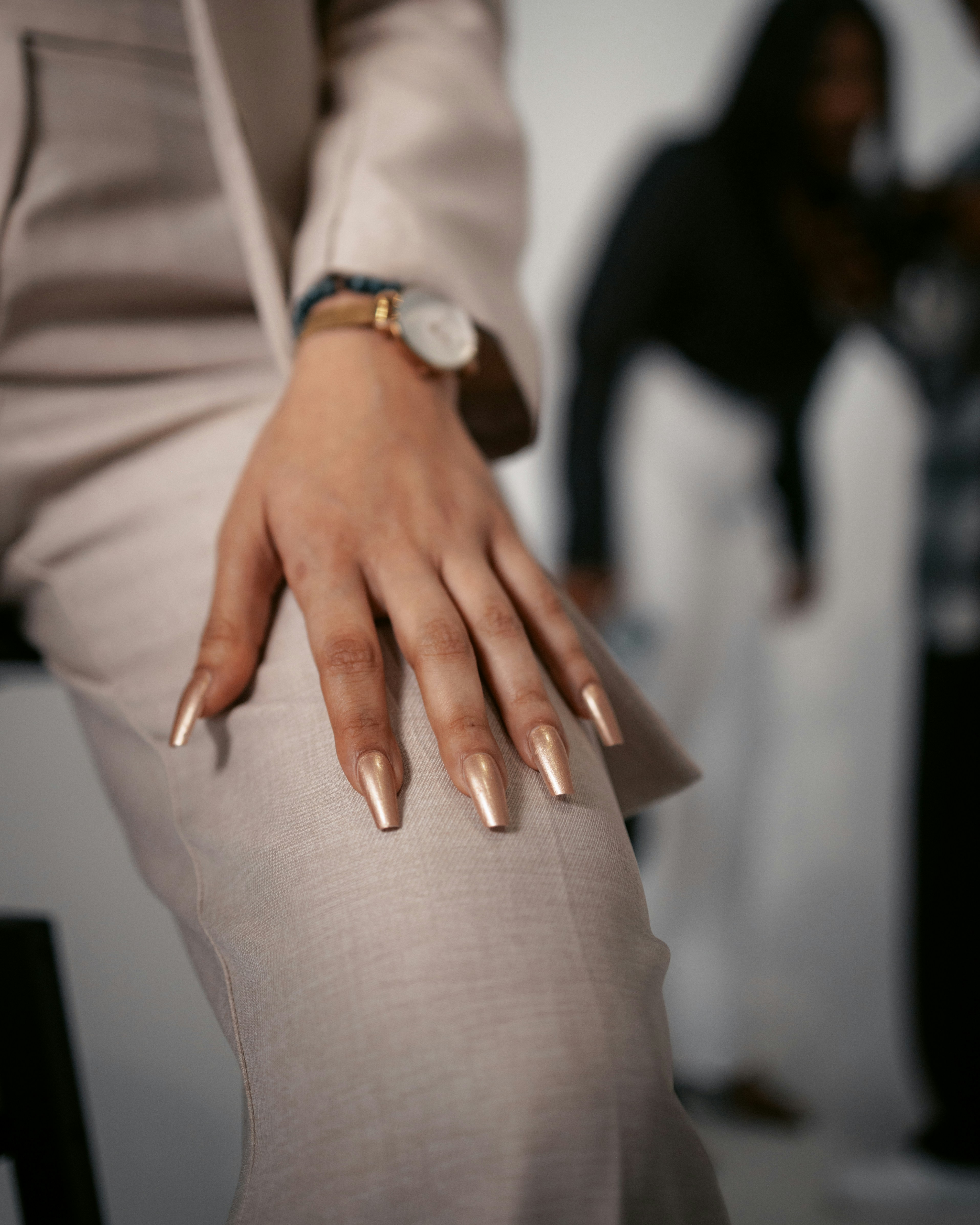 a woman's hand with gold nails and a watch