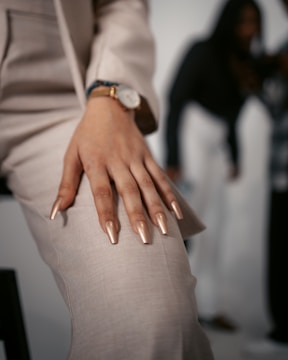 a woman's hand with gold nails and a watch