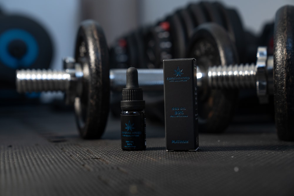 a bottle of cbd next to a pair of dumbbells