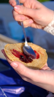 Happy customer spreading Snap Berry jam on warm toast in a cozy kitchen setting.