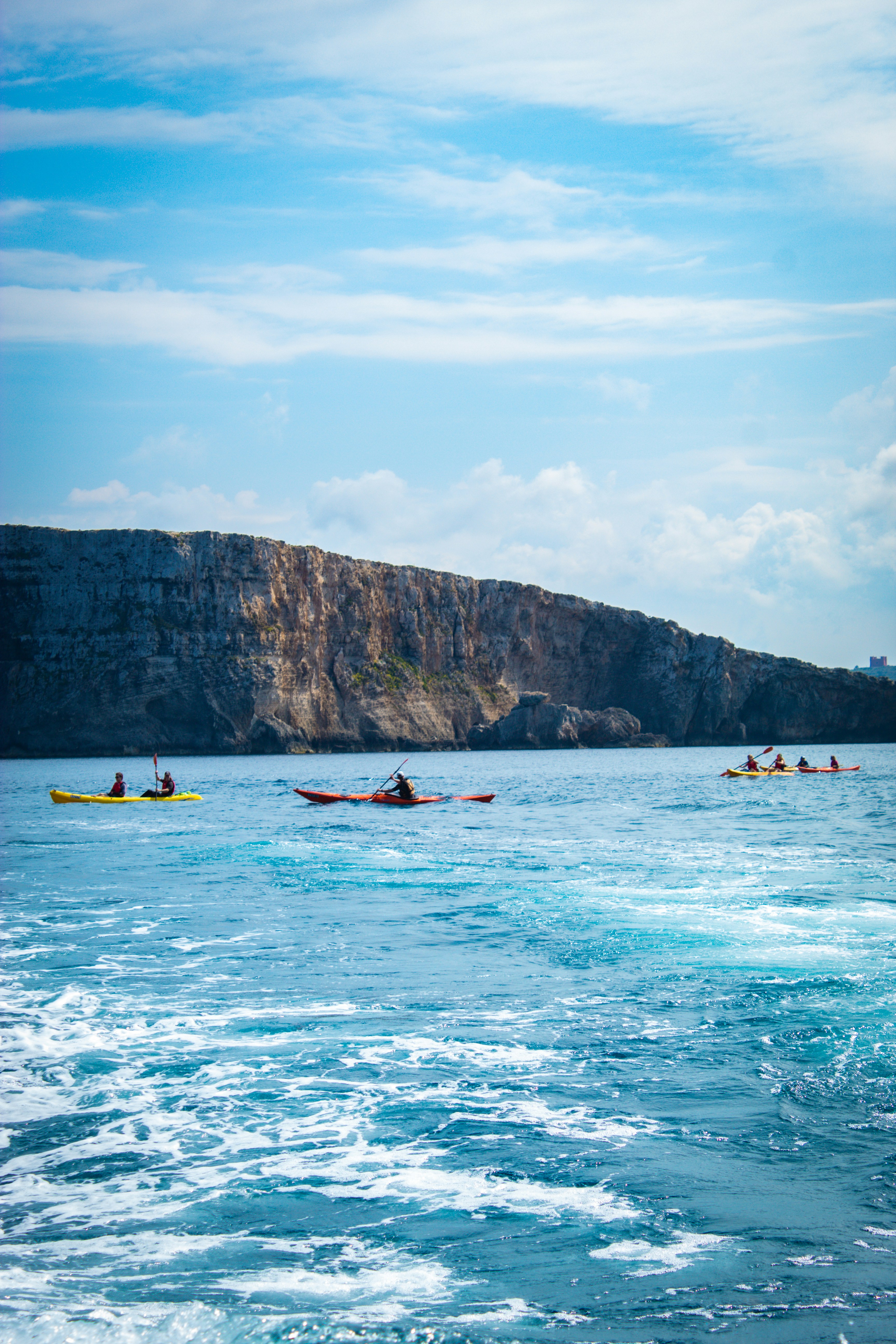 A group kayaking beneath the cliffs on the Maltese coast