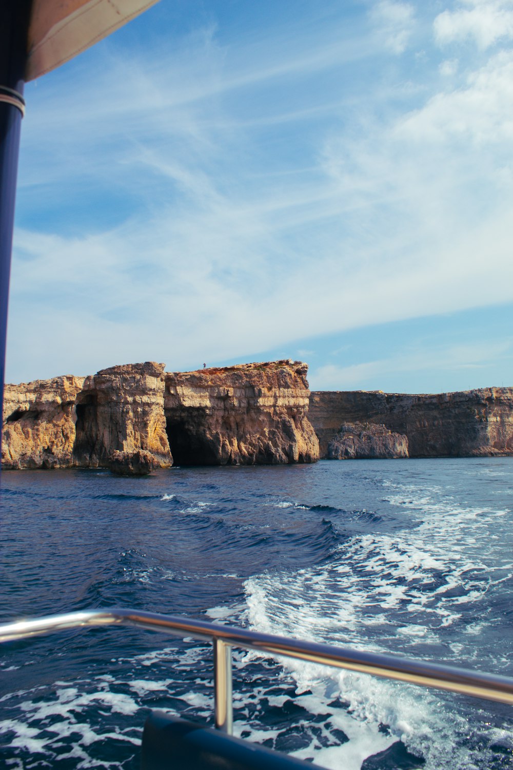 a boat traveling past a rocky cliff formation