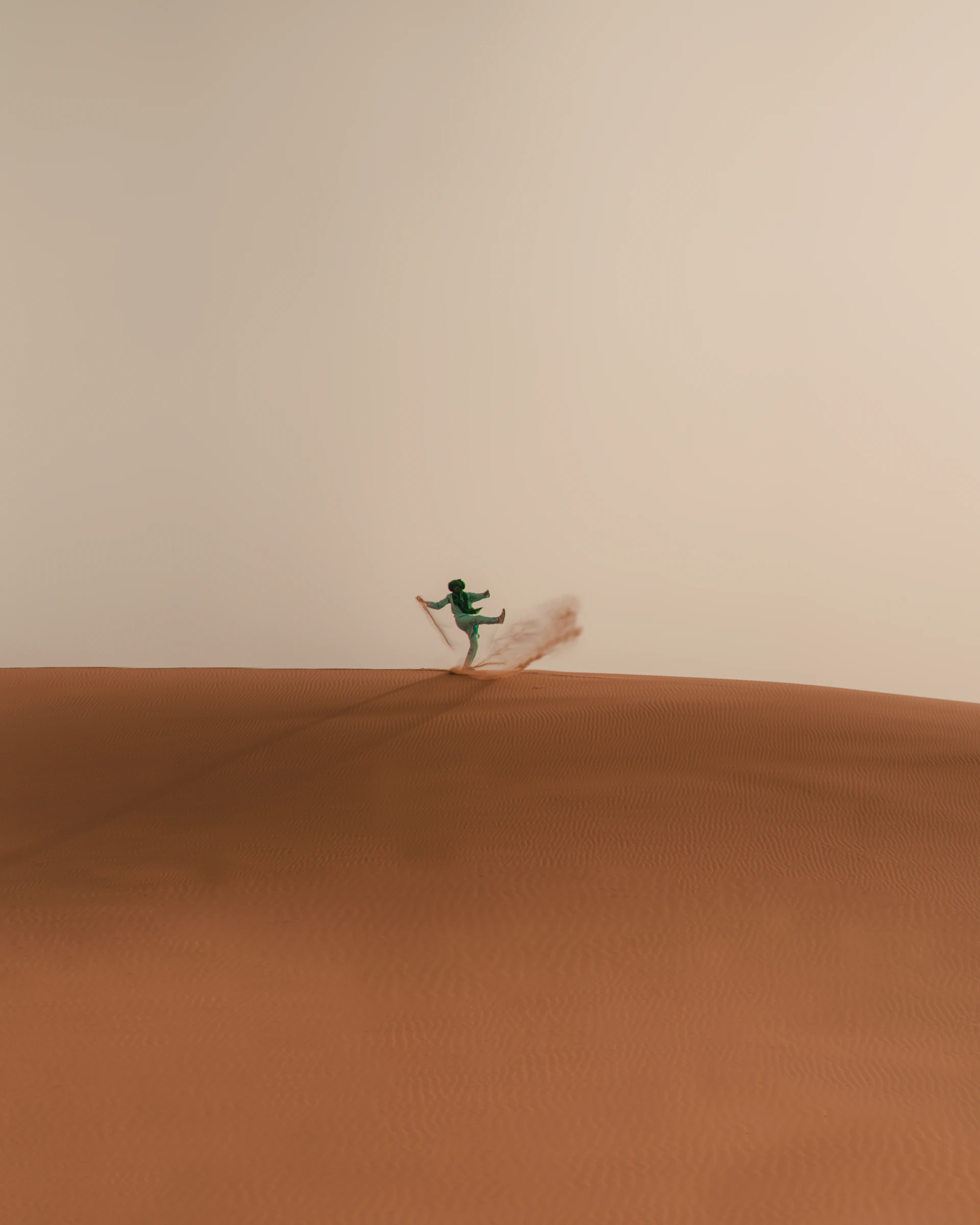 a person riding a snowboard on top of a sandy hill
