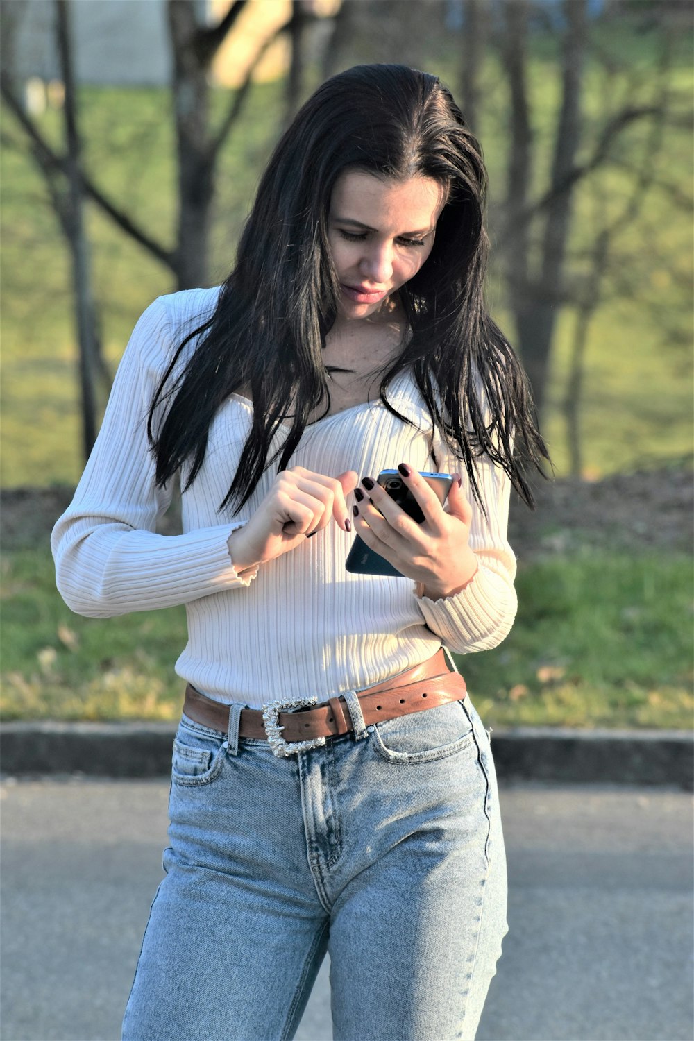 a woman in a white shirt is looking at her cell phone