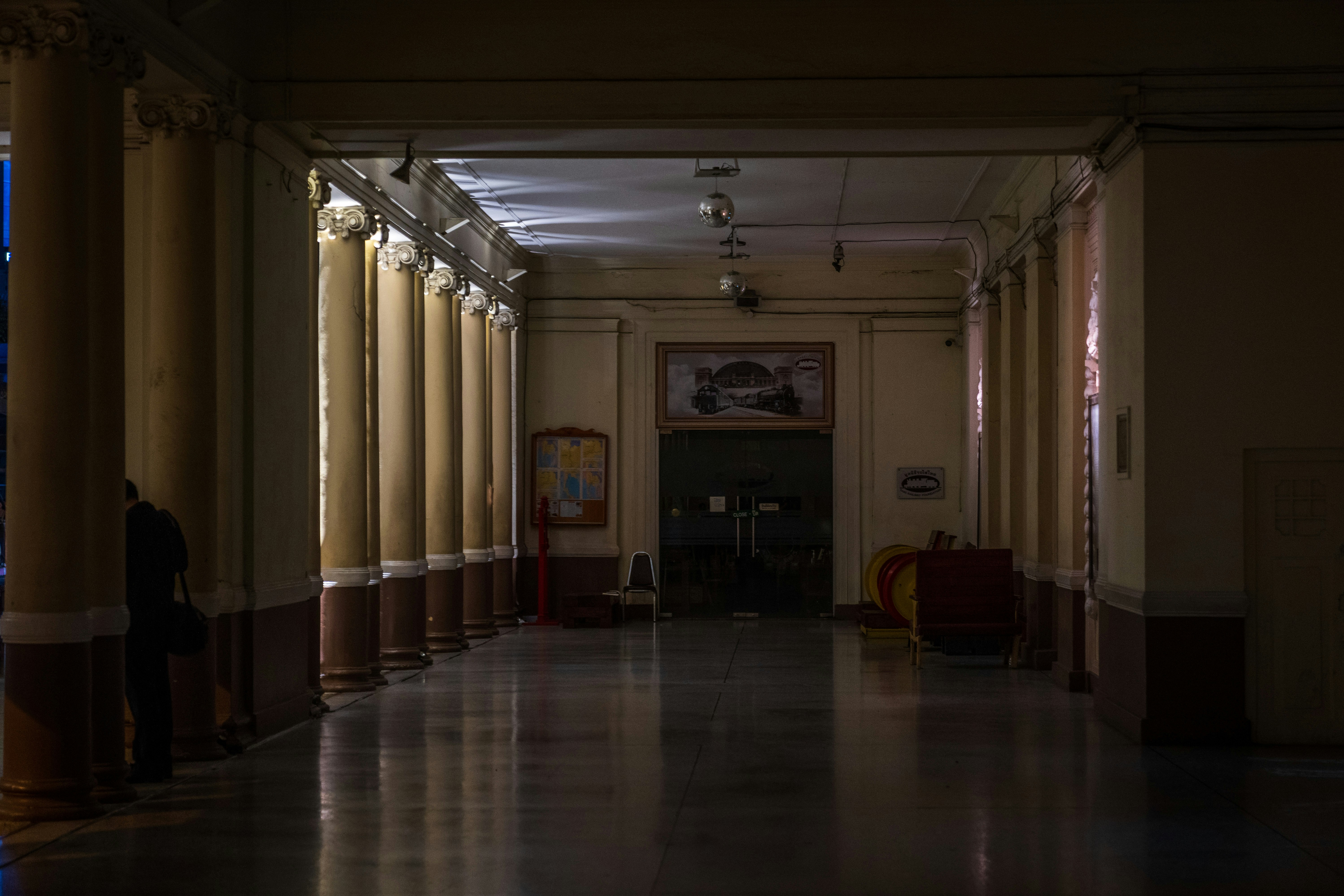 a long hallway with columns and a clock on the wall