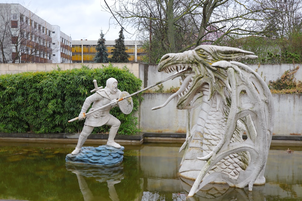 a statue of a man holding a sword next to a statue of a dragon