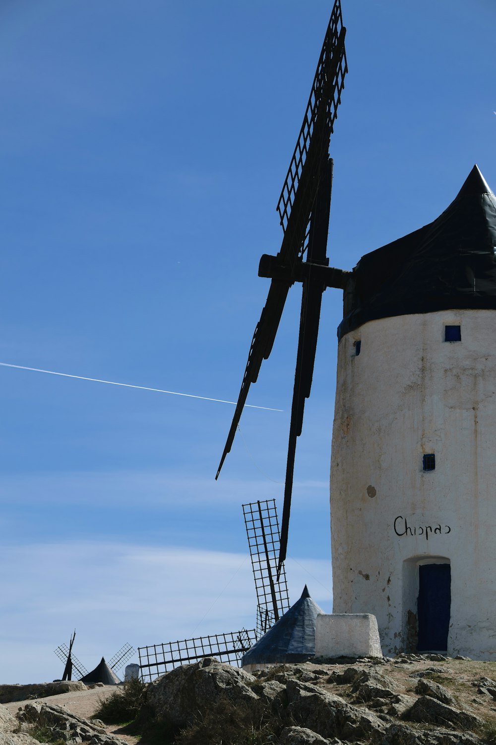 a windmill on top of a hill with a blue sky in the background