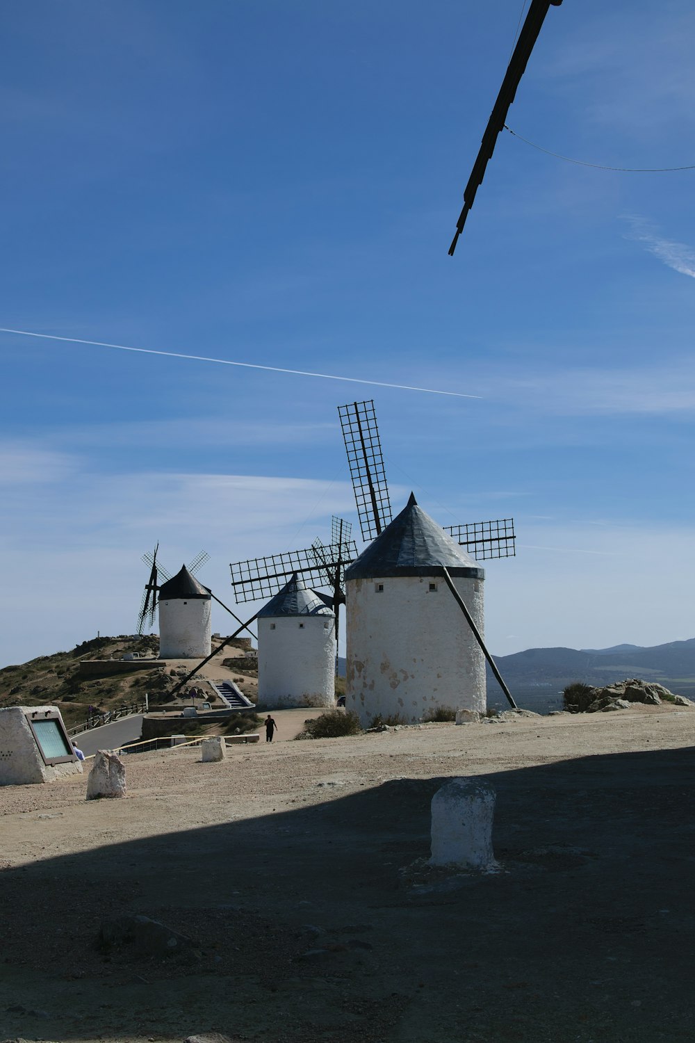 three windmills on a hill with a blue sky in the background