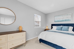 a bedroom with a bed, dresser and mirror