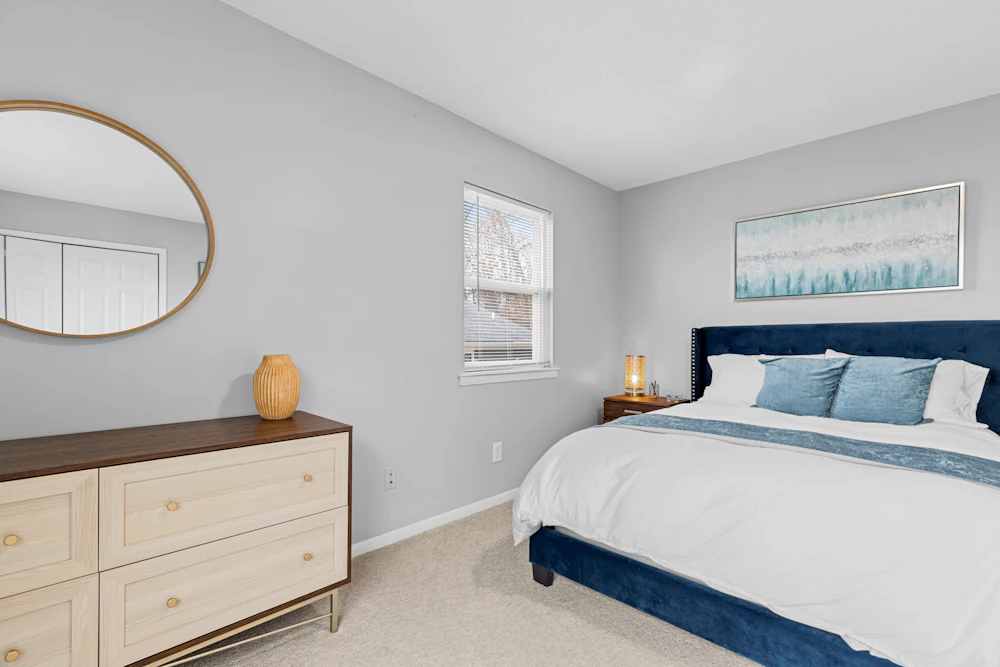 A repainted bedroom with a bed, dresser and mirror