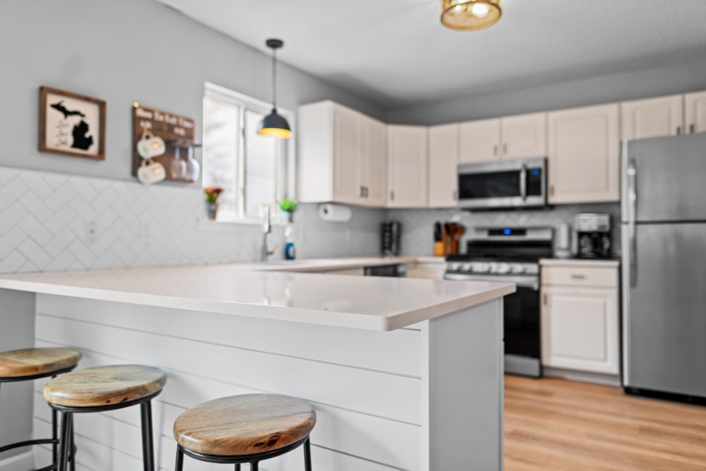 a kitchen with three stools and a center island