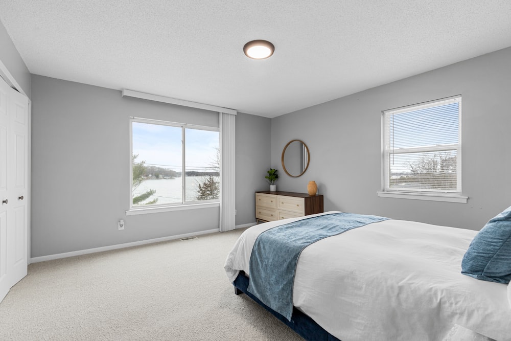 a bedroom with a bed, dresser, and two windows