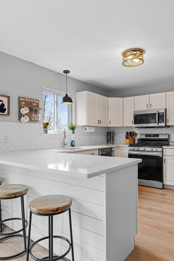 A white kitchen with a herringbone tile splashback