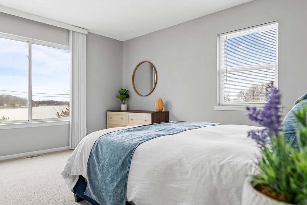 a bedroom with a bed, dresser, and two windows