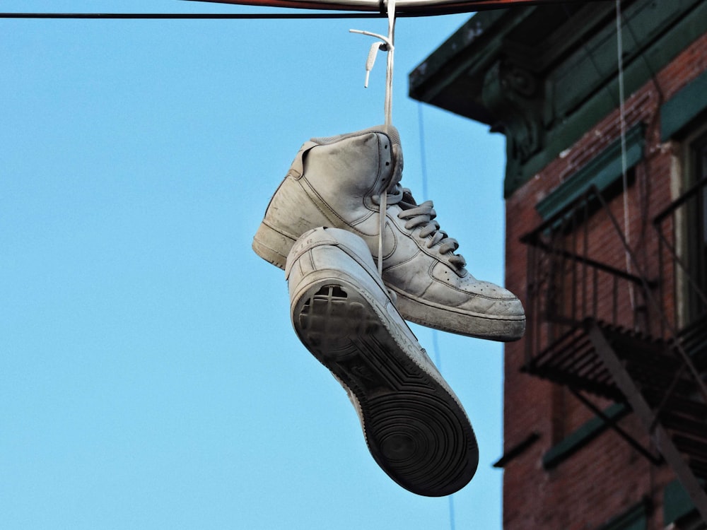 a pair of shoes hanging from a wire next to a building