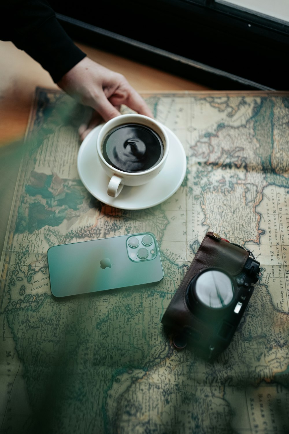 a person holding a cup of coffee on top of a map
