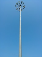 A tall lighting highmast pole illuminating a large outdoor area at dusk.