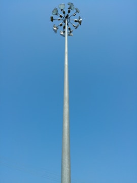 A tall lighting highmast pole illuminating a large outdoor area at dusk.