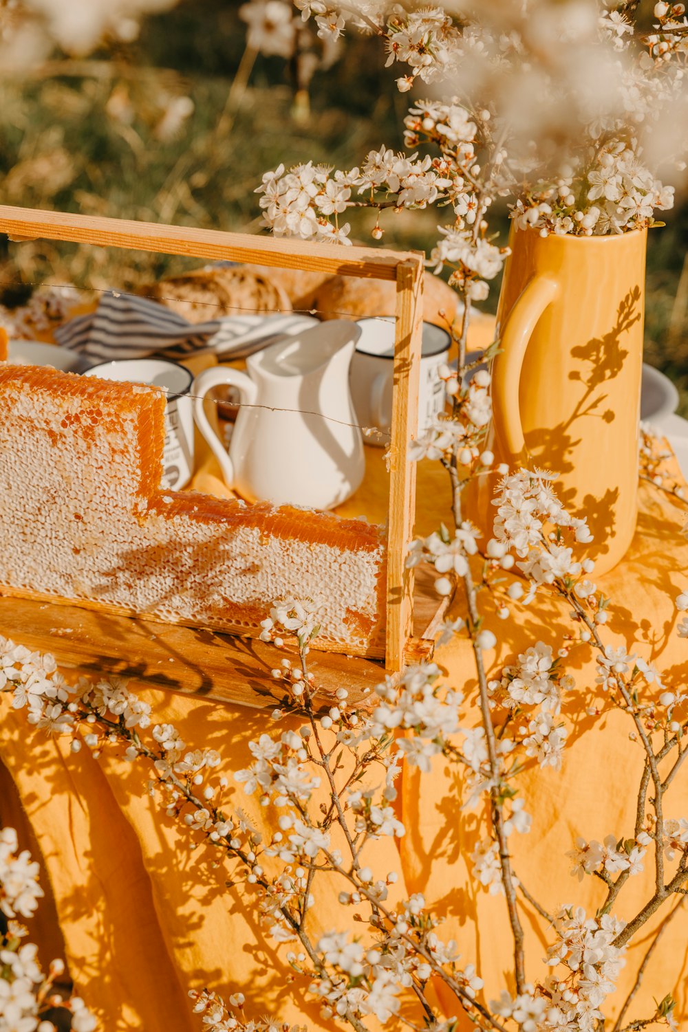 a table topped with a yellow vase filled with white flowers