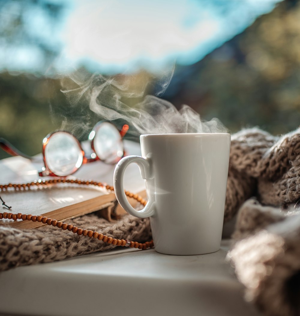 a cup of coffee on a table with a book and glasses