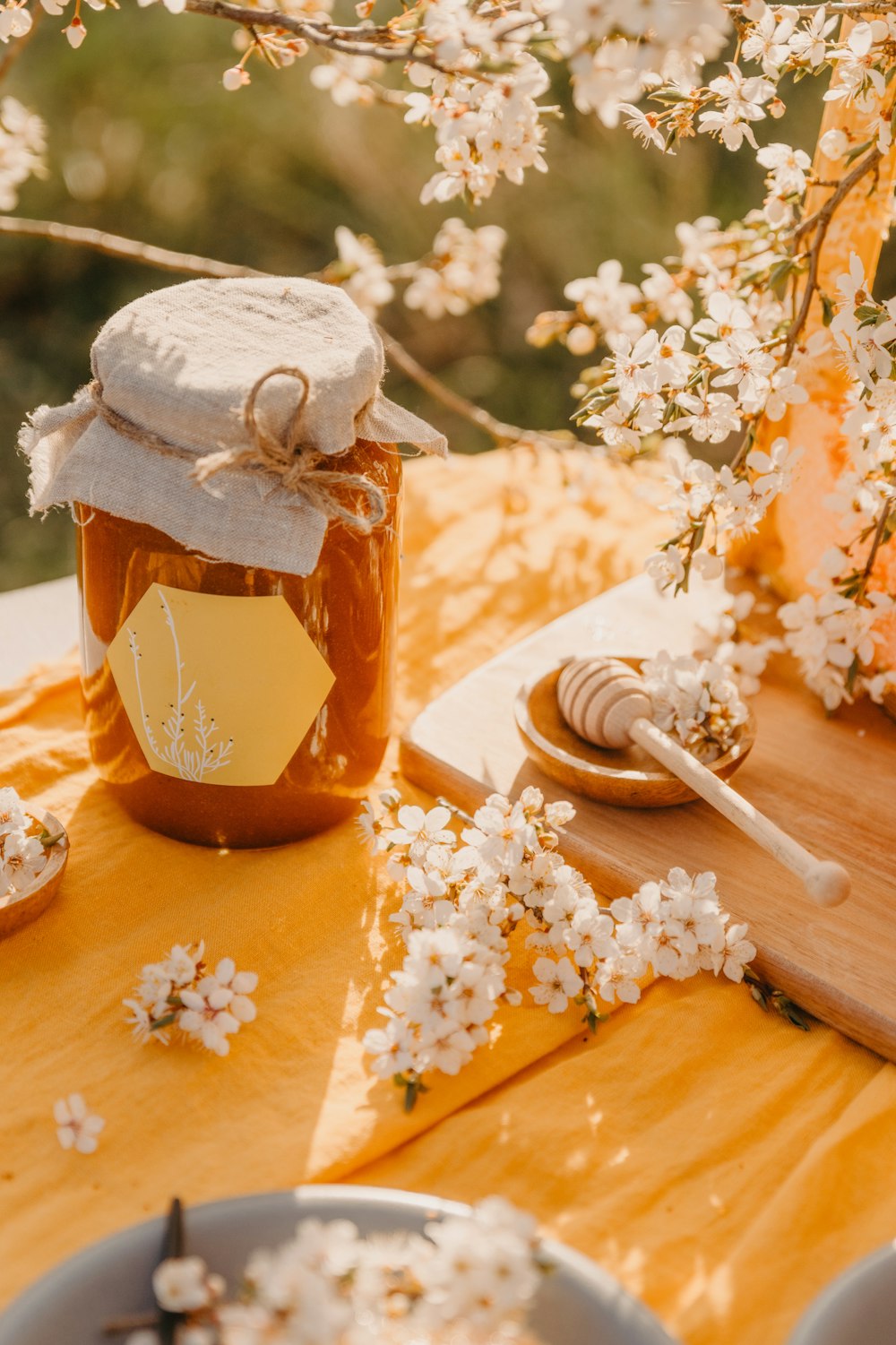 a jar of honey sitting on a table with flowers