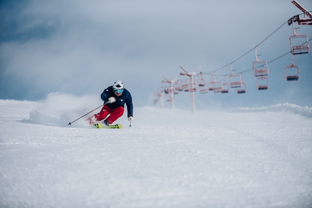 eine Person, die einen schneebedeckten Hügel unter einem Skilift hinunterfährt