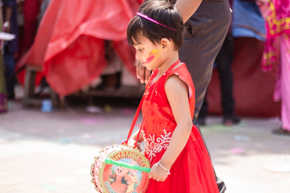 a little girl in a red dress holding a frisbee