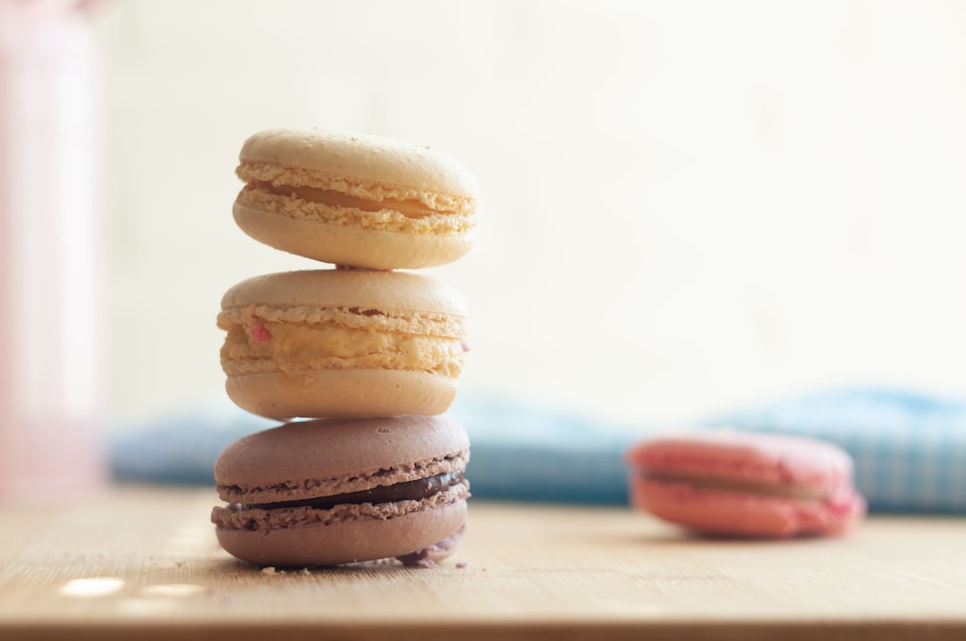 a stack of three macaroons sitting on top of a wooden table, Macaroons folded in a column