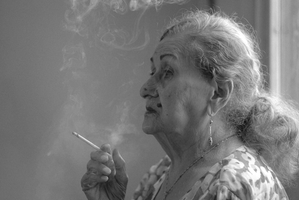 Une femme âgée fumant une cigarette sur une photo en noir et blanc