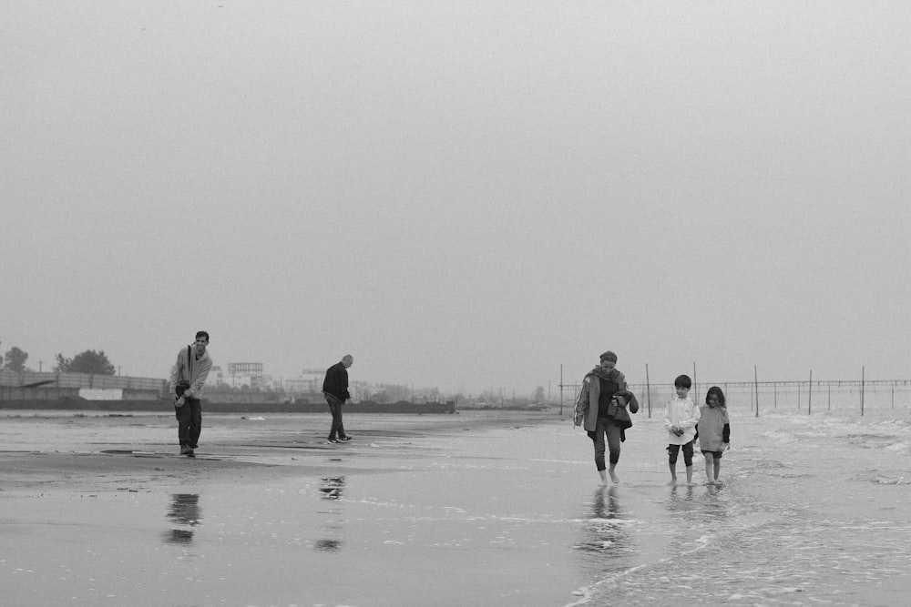 a group of people walking along a wet beach