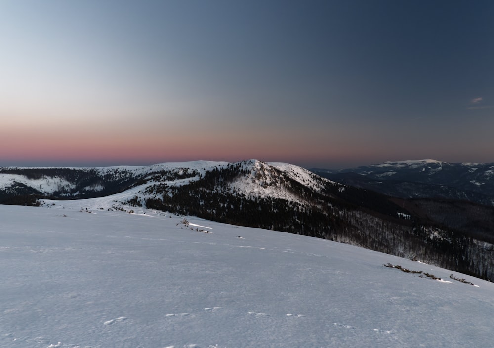 a snow covered mountain with a sunset in the background